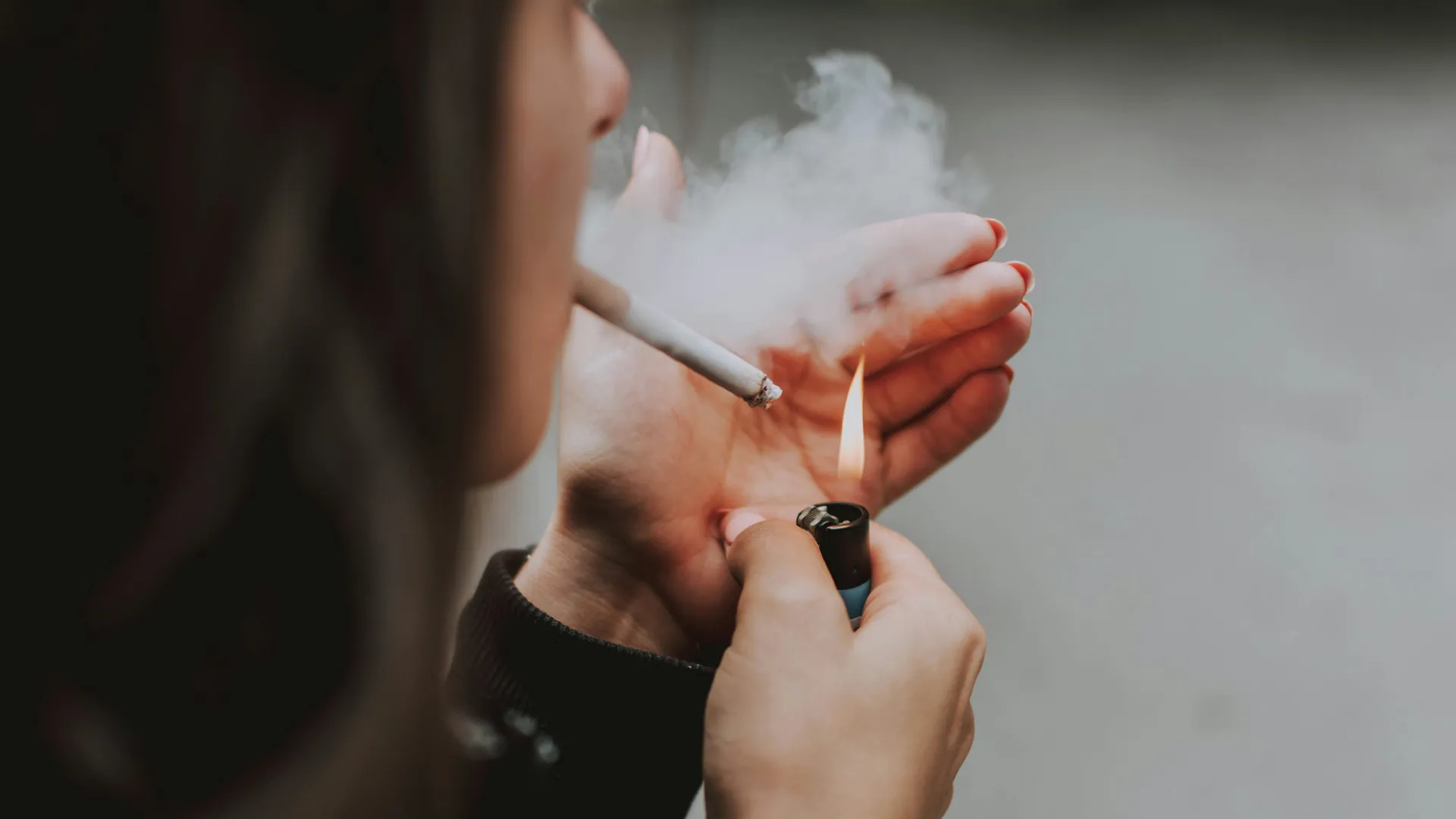 A young woman light a cigarette quickly, she is suffering from a smoking addiction