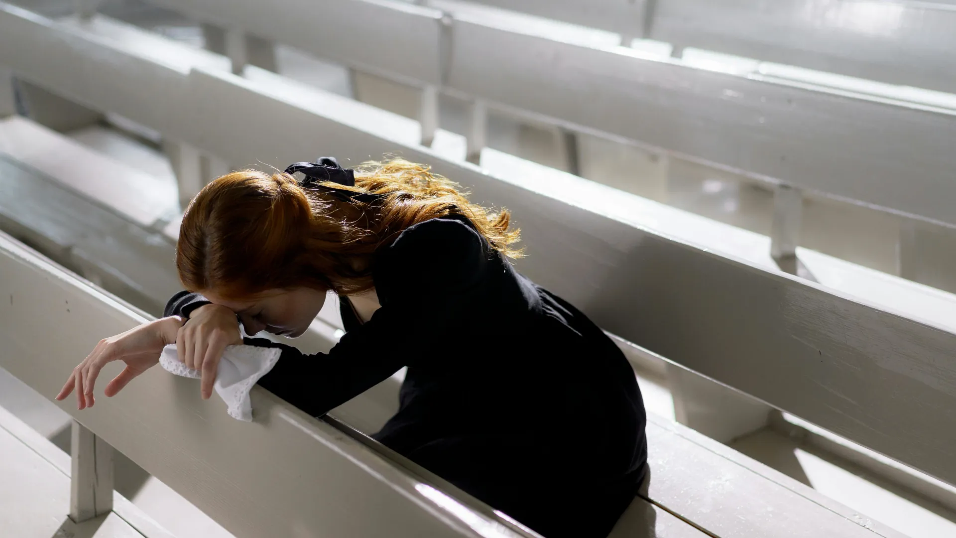 A young woman is mourning the loss of a loved one on her own in a chapel of remembrance.