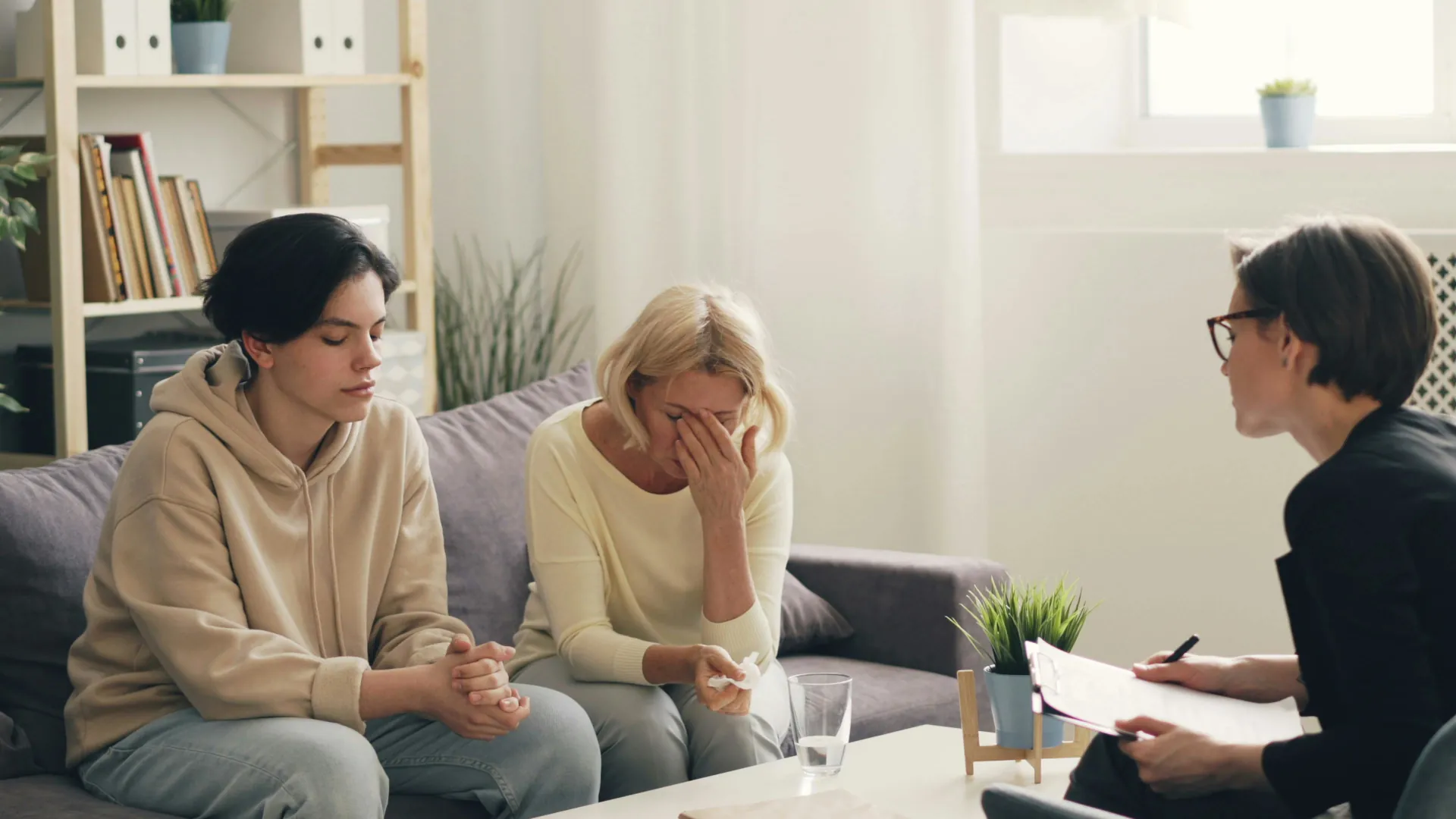 A mother looks on in distraught as her child opens up and explains their feelings to a counsellor.